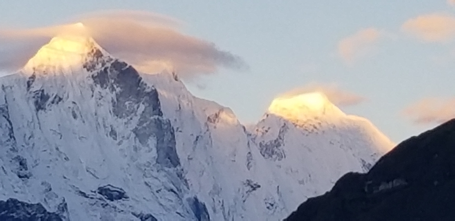 Montagnes enneigées au coucher du soleil projetant une lueur chaleureuse.