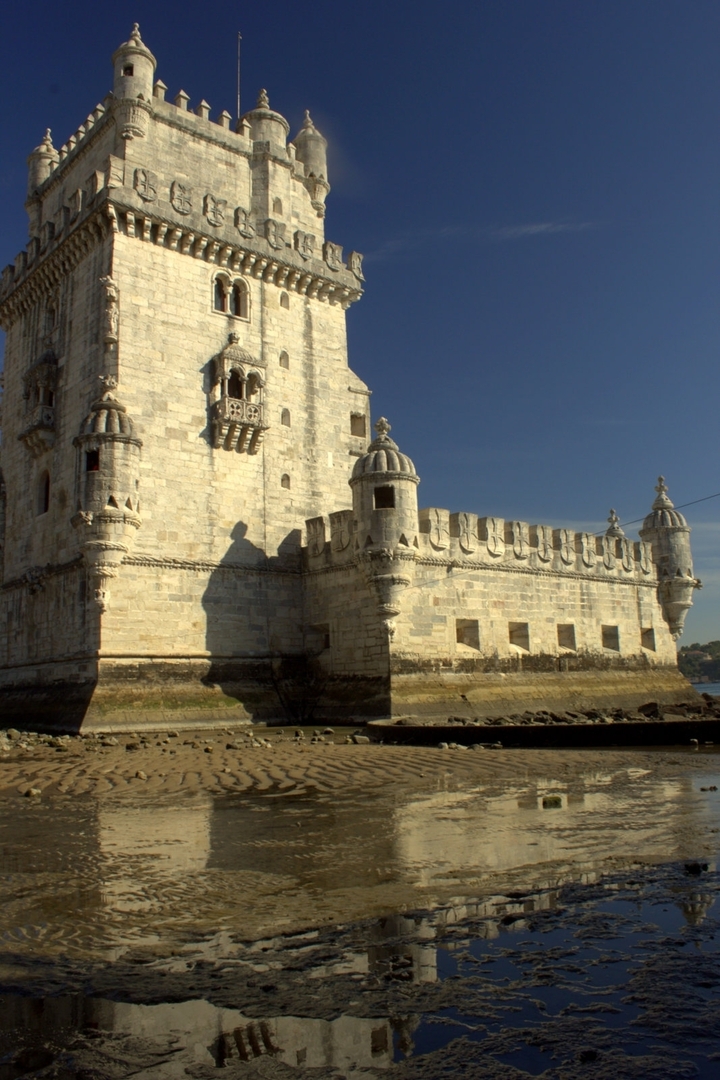 Une tour historique en pierre avec une architecture ornée sous un ciel bleu dégagé.