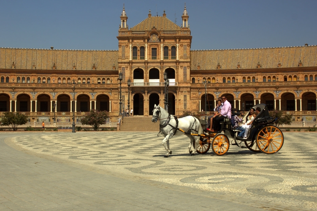 Calèche tirée par des chevaux devant un grand bâtiment historique.