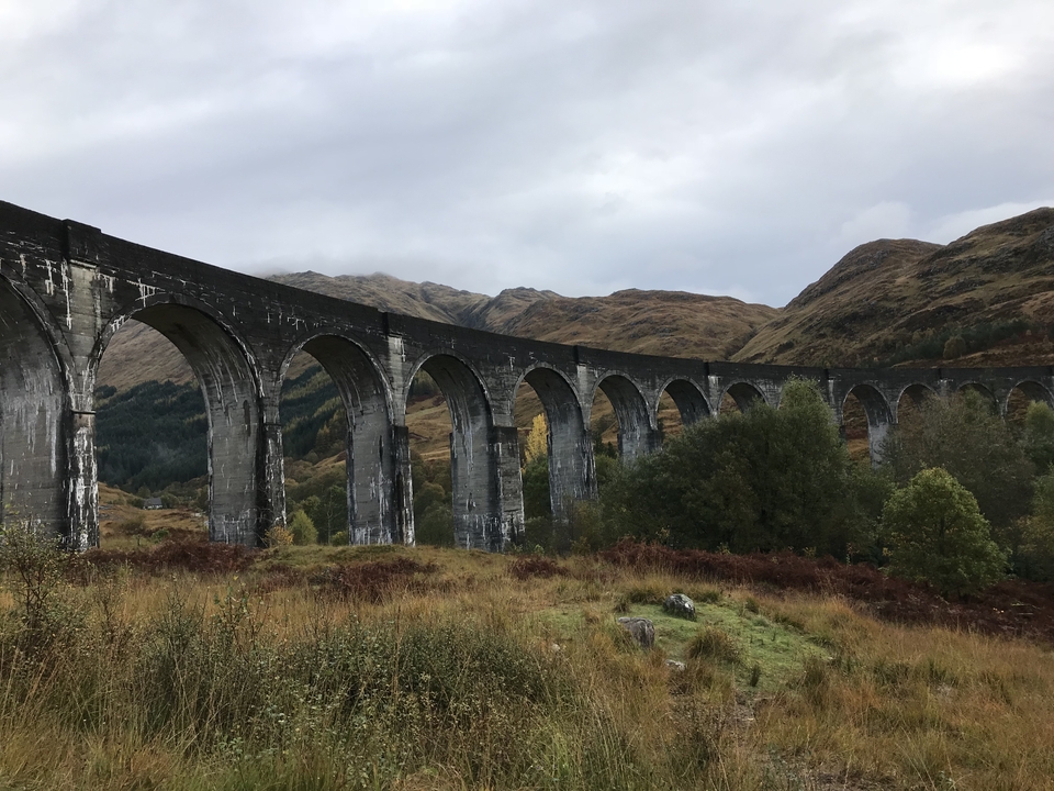 A scenic view of a historic railway viaduct amidst hills.