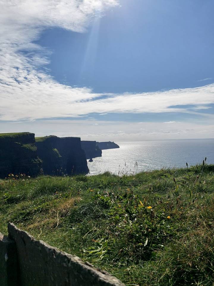 Falaises escarpées au bord de la mer, avec un ciel lumineux au-dessus.