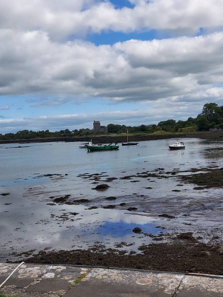 Une voie navigable tranquille avec un bateau et un bâtiment en pierre au loin.