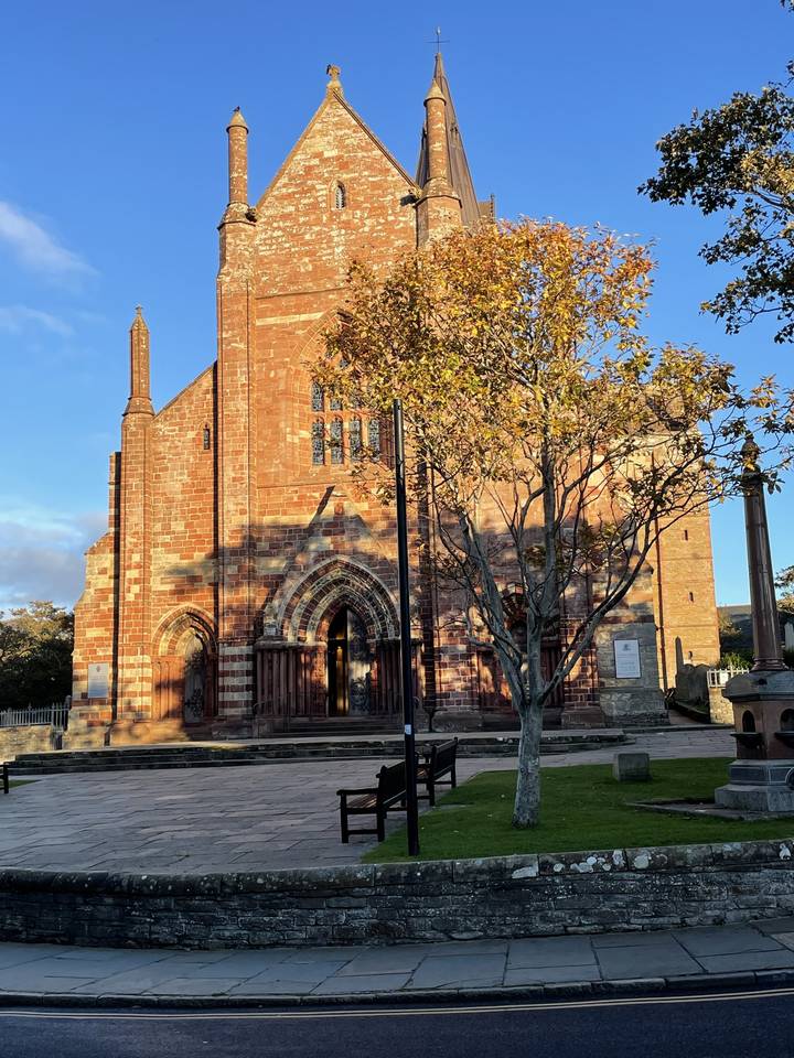 Église en briques rouges avec un arbre et un sentier.