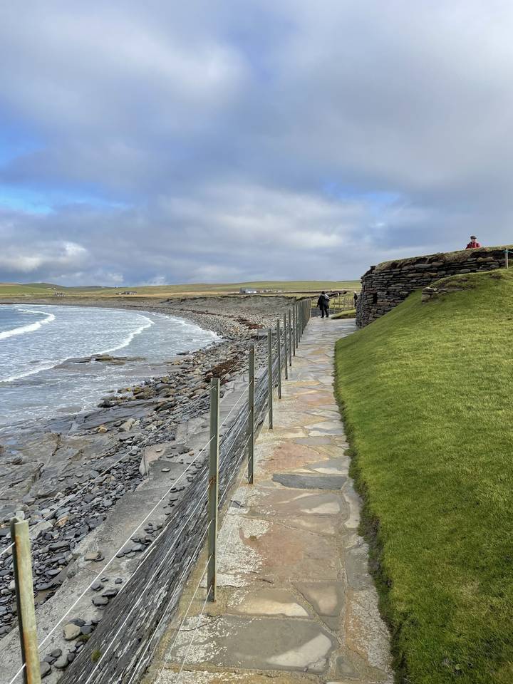 Sentier de pierre surplombant un champ herbeux.