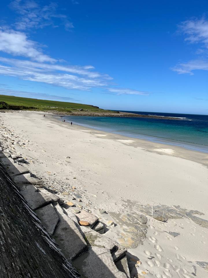 Plage de sable à côté de l'océan sous un ciel bleu.