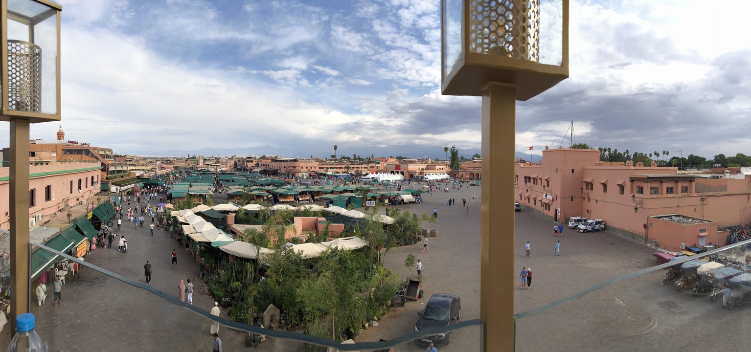 Une vue panoramique d'une place de marché animée avec des bâtiments roses.