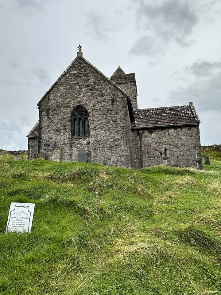 Église de pierre sur terrain herbeux.