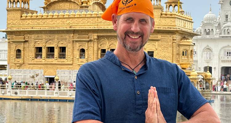 Man posing in front of a golden temple.