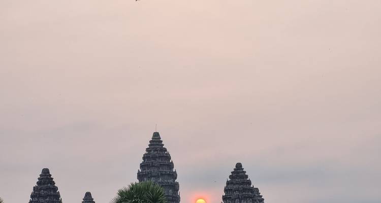 Sunset view of Angkor Wat with the sun between the temple towers.