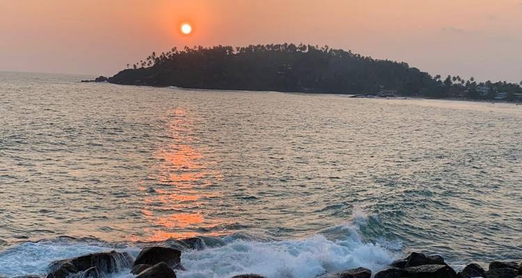 Atardecer sobre el océano con una pequeña isla en la distancia.