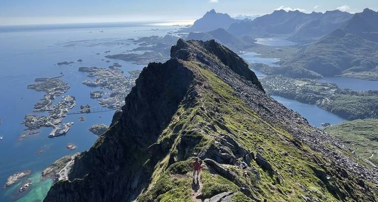 Hikers on a rocky mountain trail with a panoramic view of the sea.