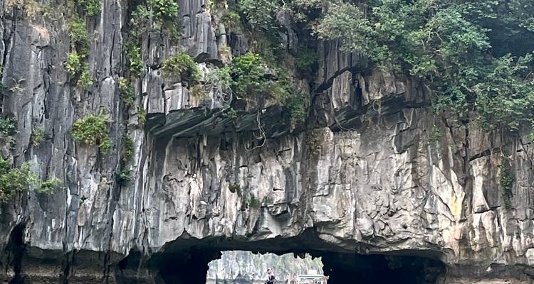 Boat entering a cave in a scenic limestone karst landscape.