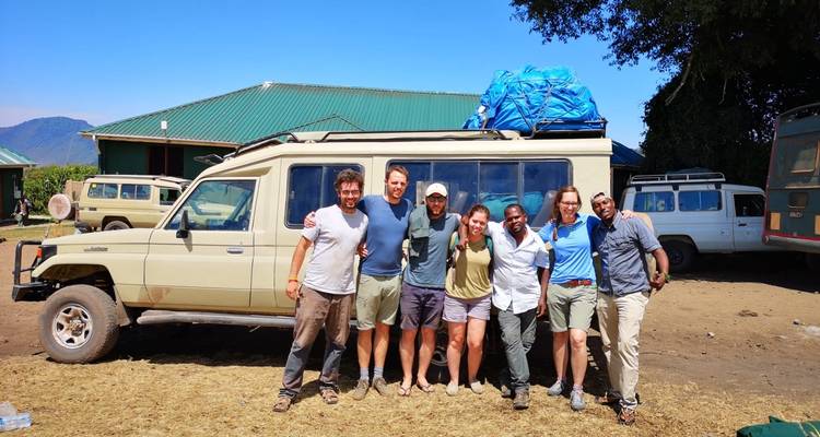 Group of people posing in front of a safari vehicle.