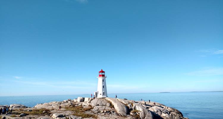 Lighthouse on rocky coast under a clear sky.