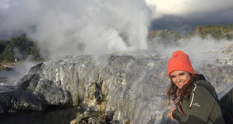 Woman posing near steaming geothermal activity.