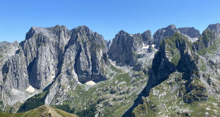 Mountainous landscape with rocky peaks and green valleys.