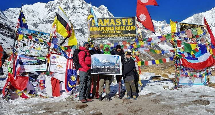Groupe de randonneurs au camp de base de l'Annapurna avec des drapeaux.