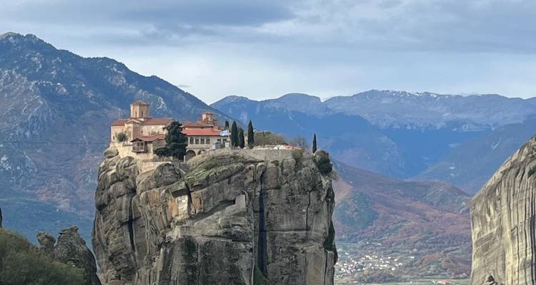 Cliff with a monastery built on top, with distant view of valley.