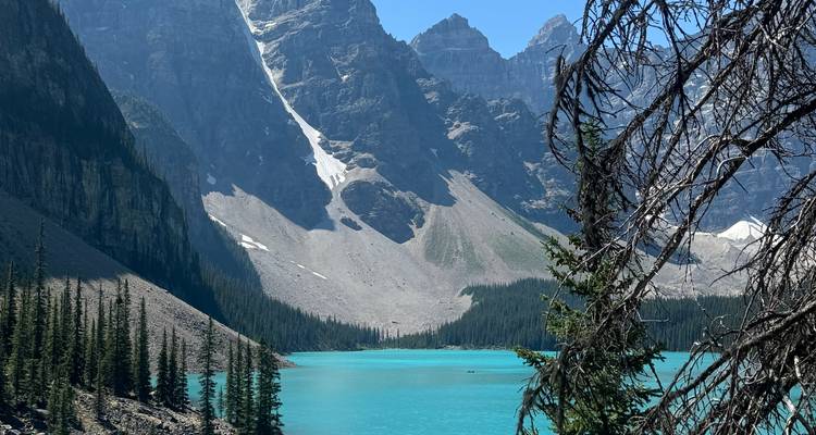 Vibrant turquoise lake with steep mountain peaks.