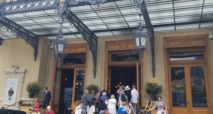 Elegant building entrance with a clock and people milling around.