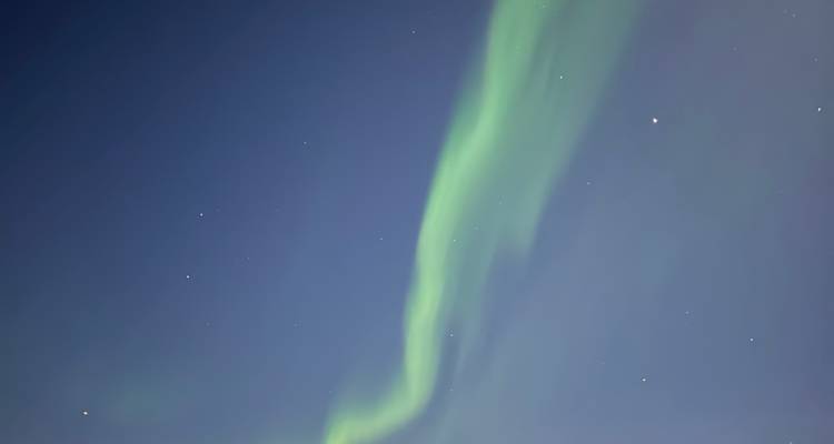 Northern lights in the night sky over a snowy landscape.