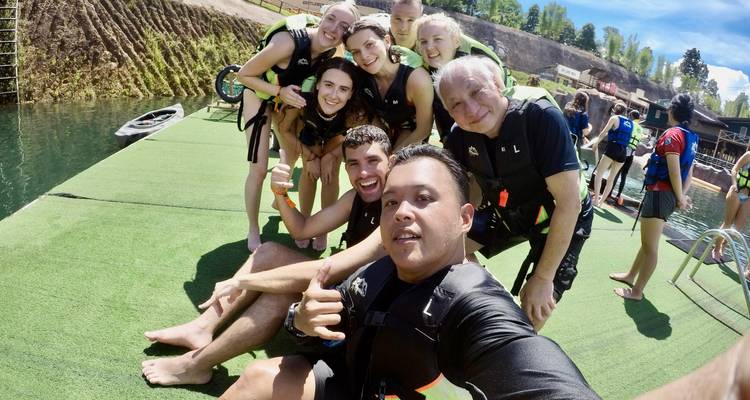 Group of people wearing life jackets posing on dock.