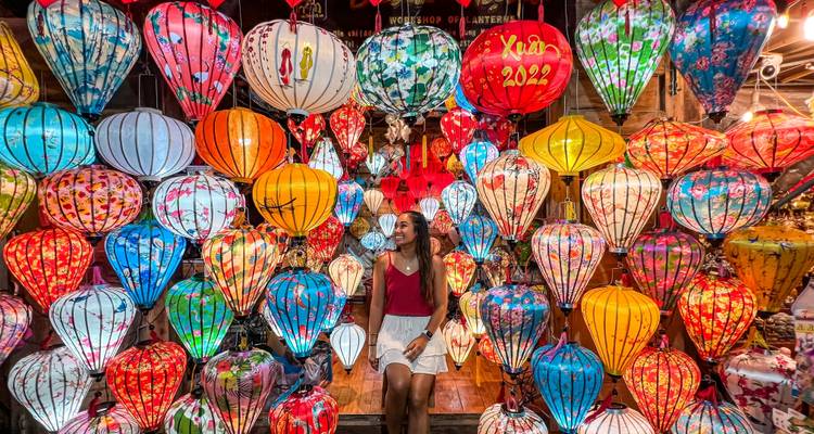 Person surrounded by colorful lanterns sitting on a step.