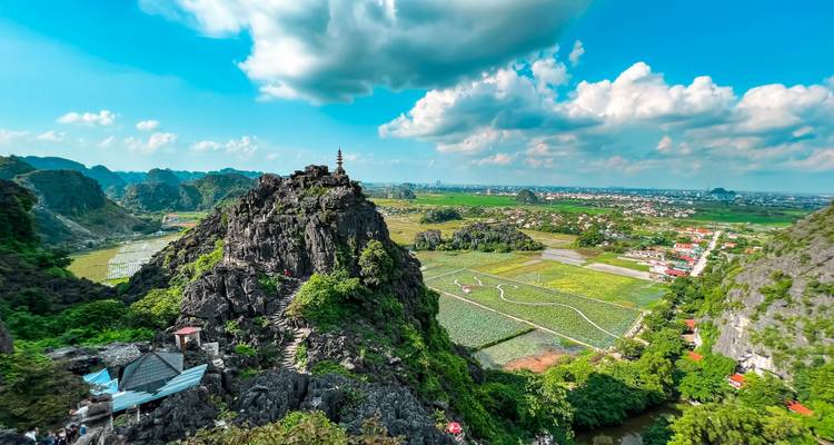 Panoramic landscape with pagoda and expansive fields.