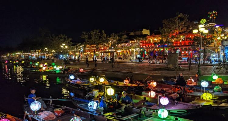 Ribera iluminada y colorida con barcos y luces por la noche.