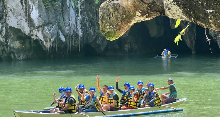 Groupe de personnes dans un bateau saluant la caméra de la main.