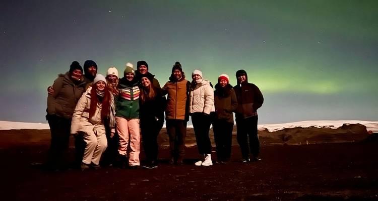 Groep mensen met het noorderlicht op de achtergrond.