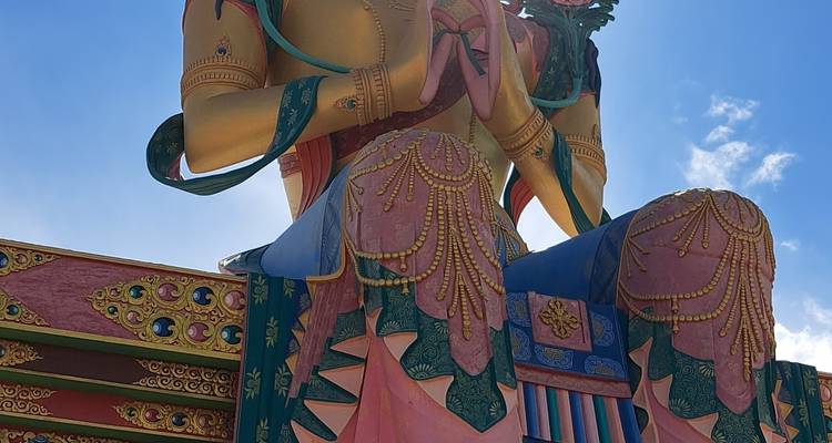 Large golden statue of a deity with mountain backdrop.