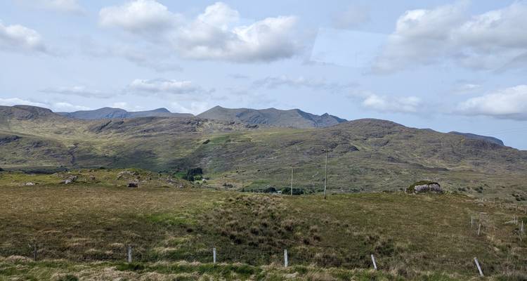 Sanfte Hügel und Weideland unter bewölktem Himmel.