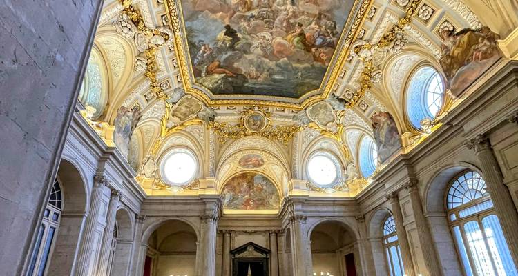 Intérieur opulent d'un bâtiment avec un plafond peint et des piliers.