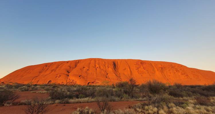 Uluru at dusk with a clear sky.