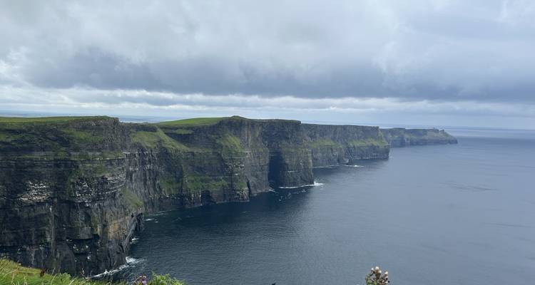 Dramatic cliffs facing the ocean under a cloudy sky.