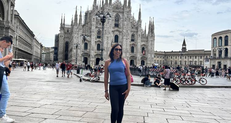 Woman posing in front of the Milan Cathedral in a busy plaza.