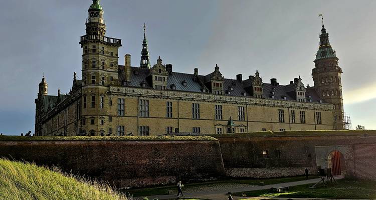 Historic castle viewed in a dramatic light with people walking below.