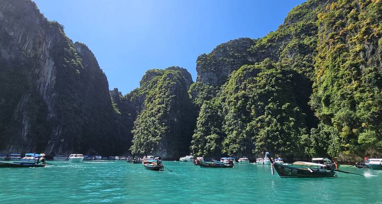 Boats and tourists in turquoise waters surrounded by limestone cliffs.