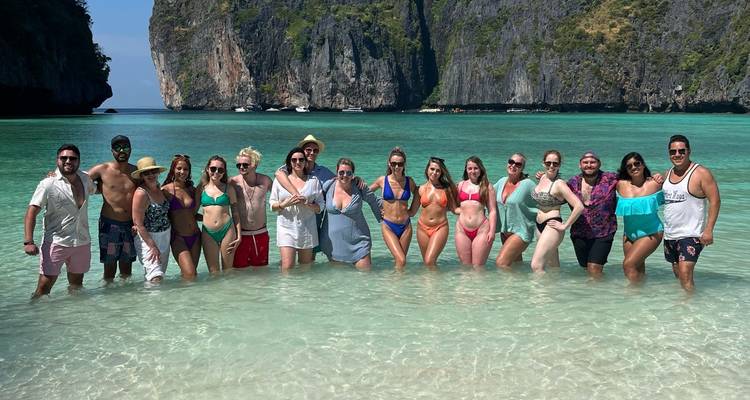 Group posing in shallow water with cliffs in the background