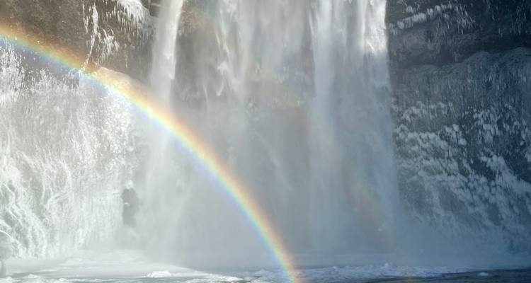 Wasserfall mit sichtbarem Regenbogen in eisiger Umgebung.