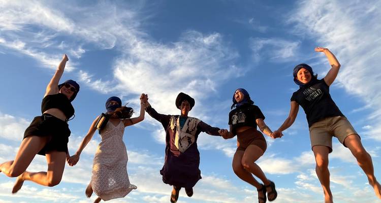 Groep mensen die springen in de woestijn.