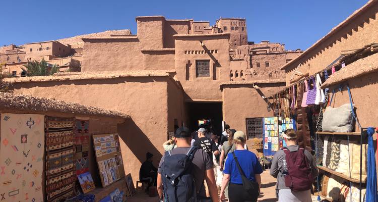 Des touristes se promenant dans un marché avec des bâtiments traditionnels.