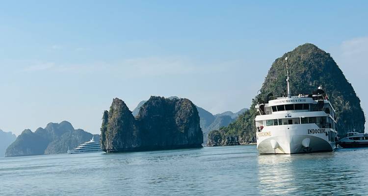 A large ship cruising near limestone formations in a bay.