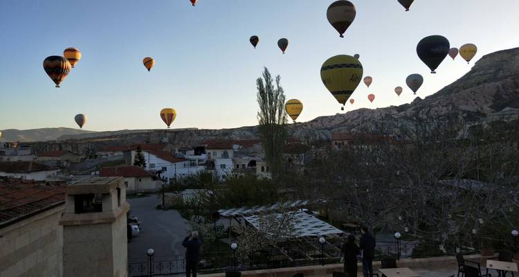 Hot air balloons in the sky over a scenic town landscape.