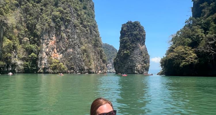 Personne nageant dans une baie tranquille entourée de hautes formations rocheuses.