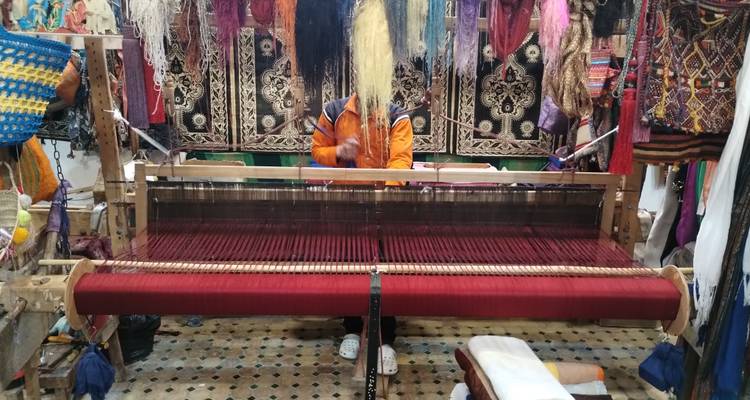 A person working on a traditional weaving loom with colorful textiles.