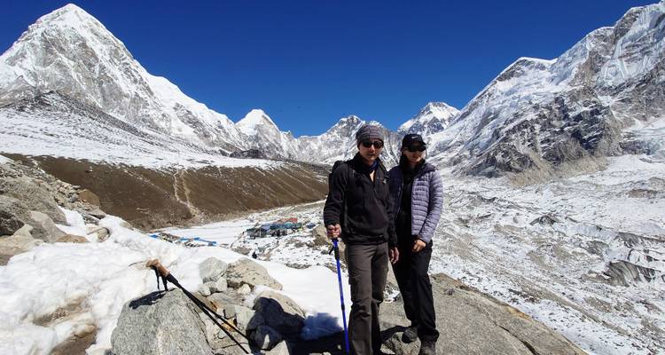 Two people in winter clothes on a snowy mountain path.