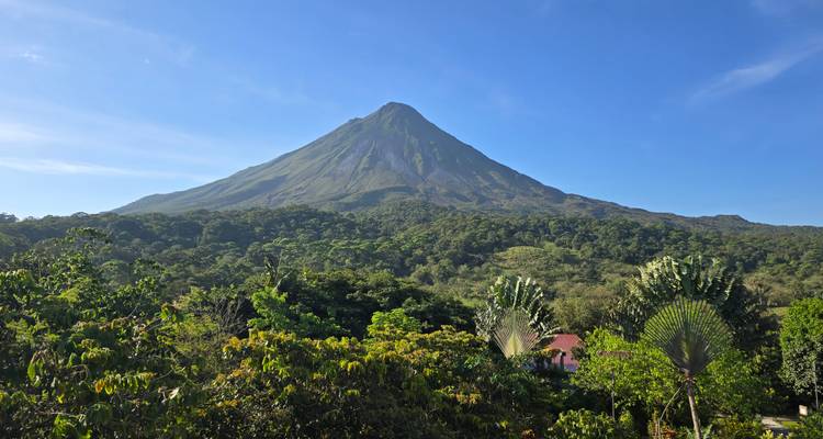 View of Arenal Volcano with a lush green forest in the foreground.