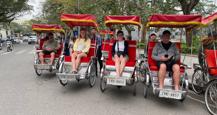 People sitting in red cycle rickshaws on a street.